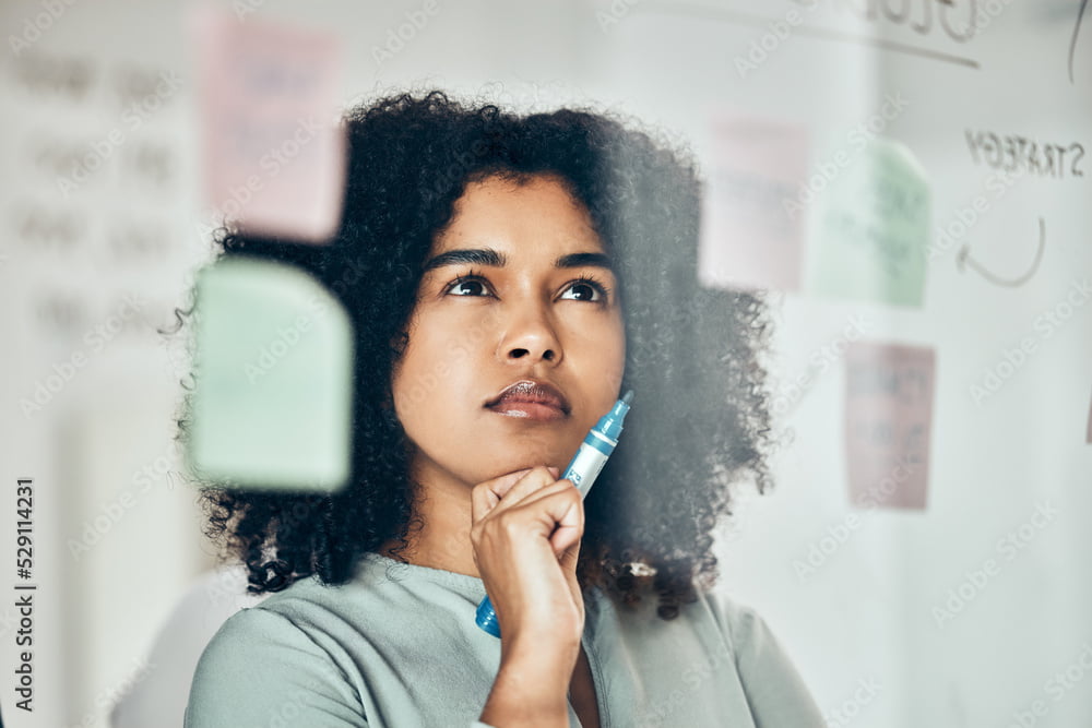 Thinking of marketing strategy on sticky note, post it paper for planning creative advertising idea and thinking of reminder on glass board. Business woman with plan for startup company at work